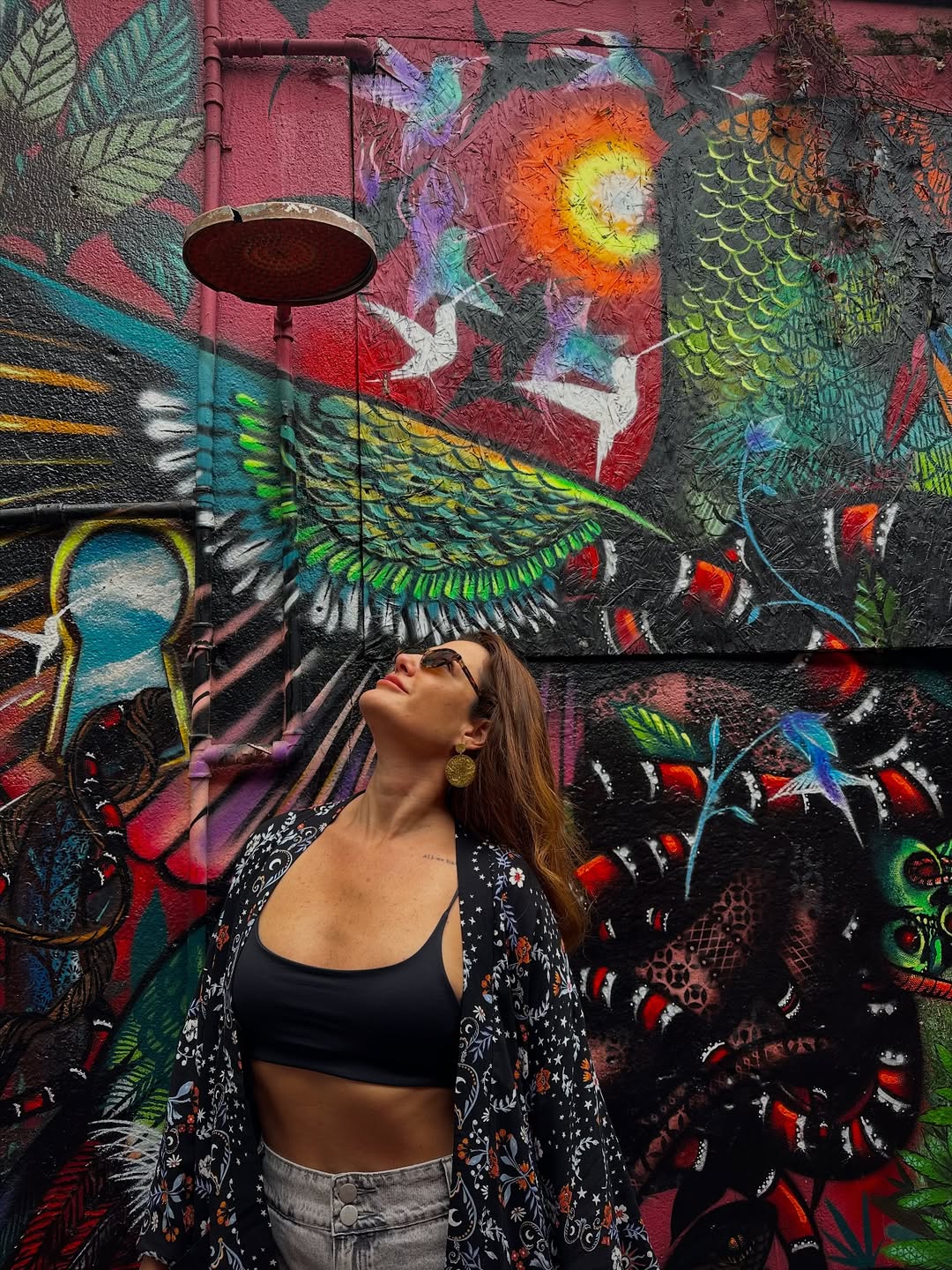 Mulher em frente a mural colorido no Beco do Batman, Vila Madalena, São Paulo.